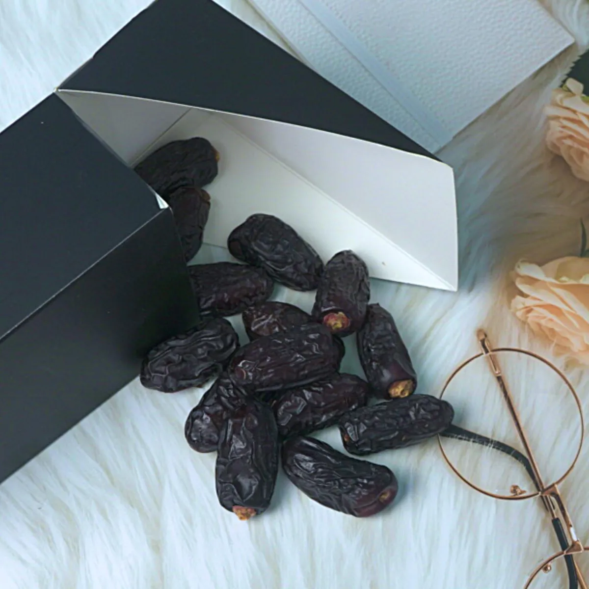 Medium Safawi dates beside a black AlSultanFood box