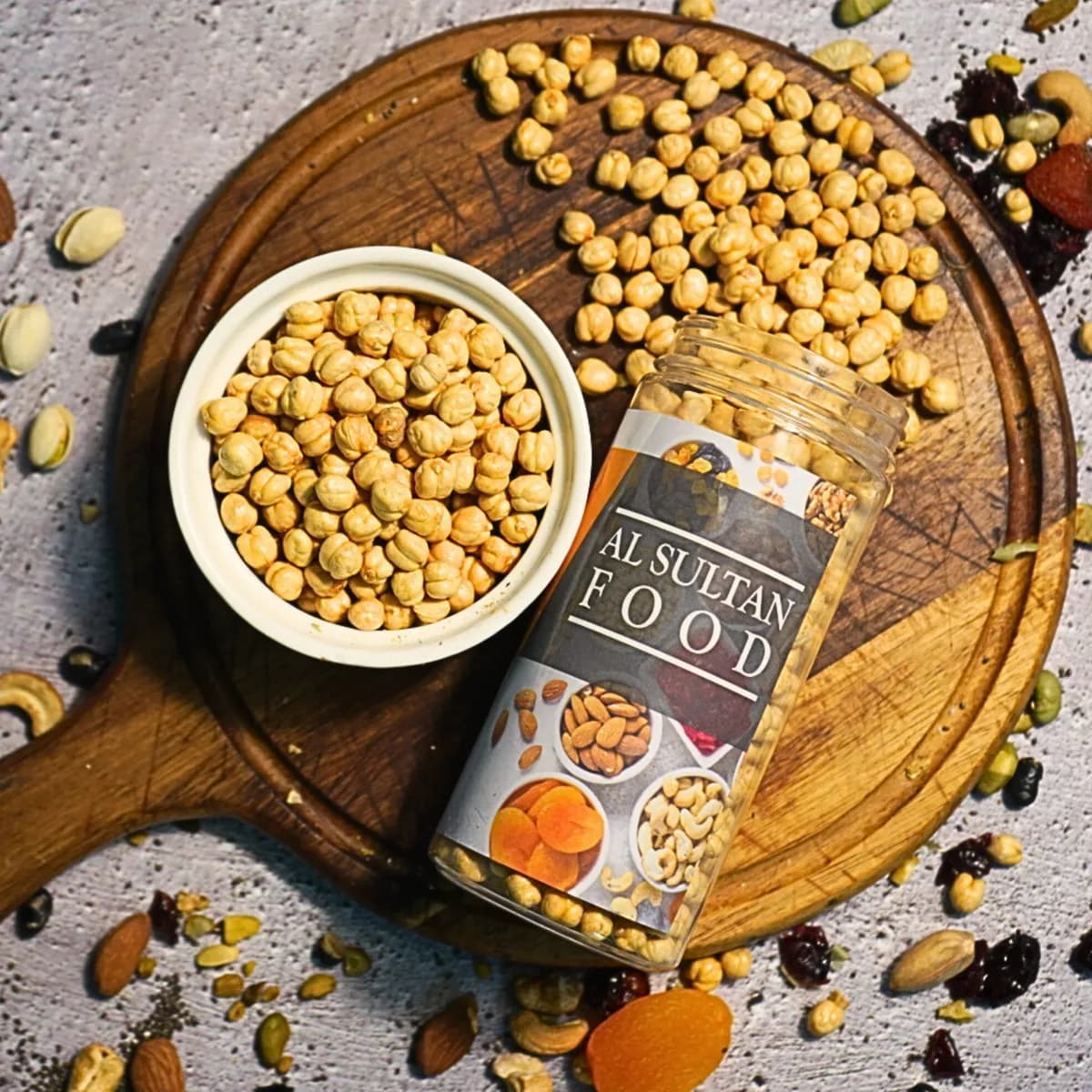 Roasted chickpeas in a white bowl next to an AlSultanFood jar on a wooden board